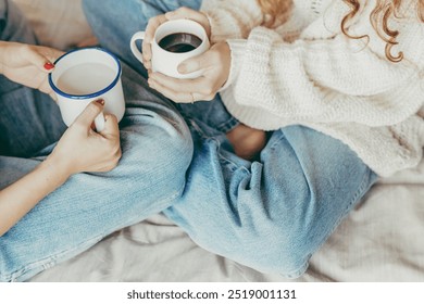 Women drinking hot drinks on bed. Friends drinking hot chocolate and milk in bed. Two friends having a cozy break in bed during Autumn. Two girls relaxing, drinking hot drinks. - Powered by Shutterstock