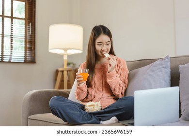 Women drinking orange juice and eating snack while watching movie on laptop in lifestyle at home. - Powered by Shutterstock