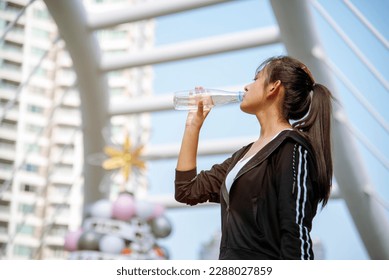 Women drinking water bottle running exercise in modern city wear wellness sportswear outside. Young woman workout outdoor exercising on bright sunny outside. Healthy wellness lifestyle woman concept
