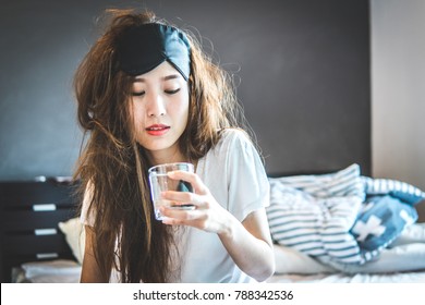 Women Drinking Water By The Bed After A Night Of Drinking Alcohol. The Day After Hangover And Intoxitation.