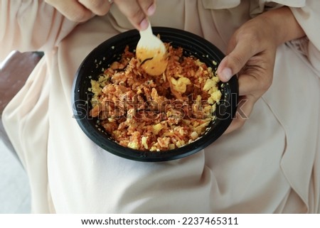 women eating curry chicken and rice in a take away plastic packet 