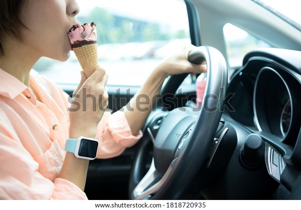 Women eating ice\
cream while driving a car