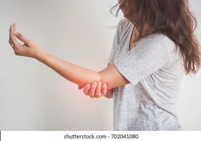 women elbow pain, holding hand to spot of elbow pain.Arm pain and injury concept.