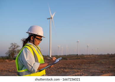 Women Engineer Working And Holding The Report At Wind Turbine Farm Power Generator Station On Mountain,Thailand People