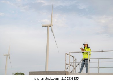 Women Engineer Working And Holding The Report At Wind Turbine Farm Power Generator Station On Mountain,Thailand People