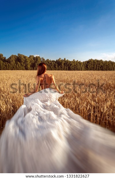 Women enjoying
nature in meadow. Bride in wedding  posing a wheat field in a warm
summer day against a blue sky
