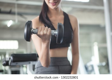 Women are exercising. She raises dumbbells to build muscle.