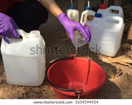Women experimented with pouring a solution or formic acid into a red plastic container at farm. Design concept for mixing agricultural chemicals.