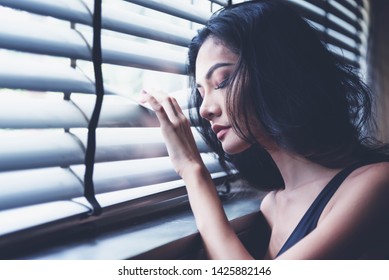 Women feeling no freedom. Women holding the louver window imprisoned make no freedom or lack of freedom. Girl lean on the window dark room feeling lonely. Life issues and problem