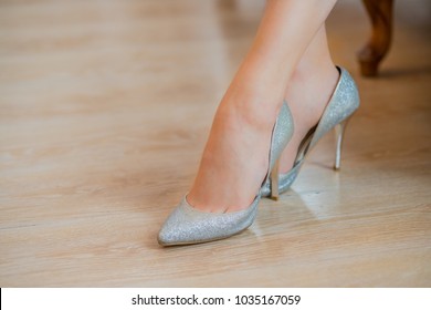 women feet in Luxury spring sommer women's shoes. female stylish slippers on the wood floor. Fashionable woman. Silver shiny footwear with high heels. wedding shoes with pointed toe. Copy space