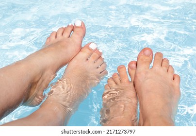 Women Feet In Pool Water.female Friends Or Couple,lovers, Having Fun,playing With Legs Under Water.summer Sunny Day,vacation Concept.white Color Nail Polish, Shellac Pedicure.