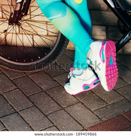 Women feet in sneakers alongside a bicycle