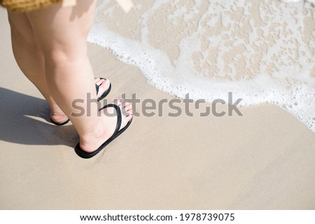 women feet are stand on the sandy beach