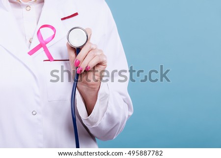 Women fight for health. Breast cancer tumor concept. Pink ribbon and blue stethoscope on white medical uniform. Doctor holding medical equipment.