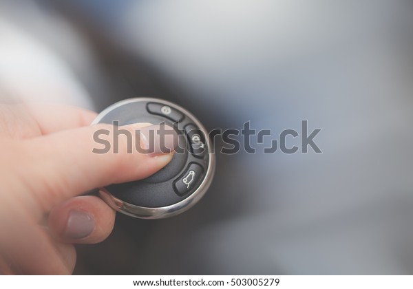 Women finger on car remote key, intentional\
blurred background with copy\
space.