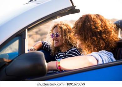 Women friends in a convertible car smiling and having fun together during travel - concept of happy people driving and enjoying transport on vehicle - summer holiday vacation outdoor - Powered by Shutterstock