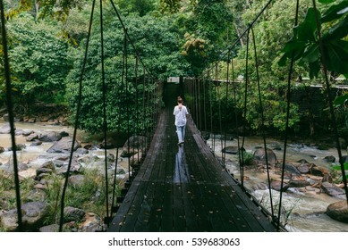 Women goes on the rope bridge across the river in the forest after rain, at Raksawarin hotspring, Ranong ,Thailand - Powered by Shutterstock