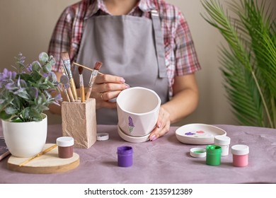 Women In Gray Apron Paint A White Flower Ceramic Pot