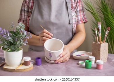 Women in gray apron paint a white flower ceramic pot - Powered by Shutterstock