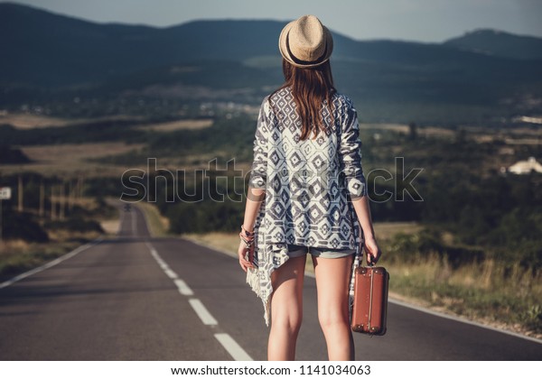 women is hailing a car on a road. Thumbing a\
ride. Outdoors vacation..