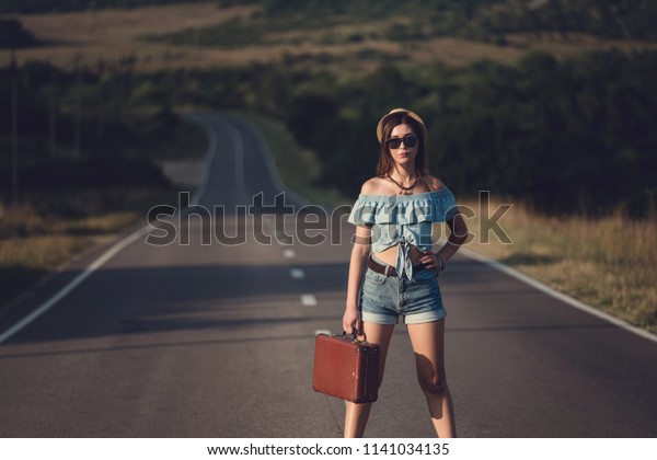 women is hailing a car on a road. Thumbing a\
ride. Outdoors vacation..