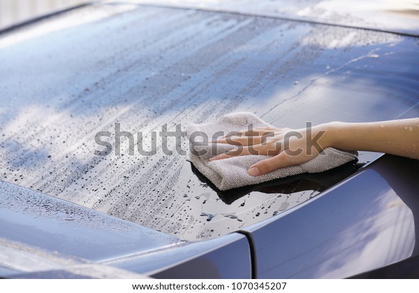 women hand dry wiping car surface with\
microfiber cloth after\
washing.