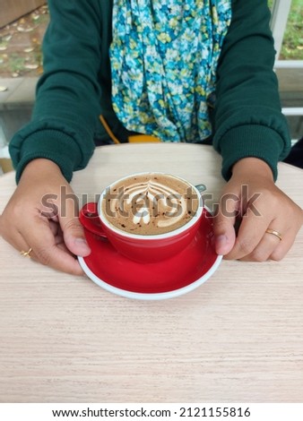 Women hand hold cup of coffee latte art on the wooden table. Isolated background. Selective focus. Coffe time concept
