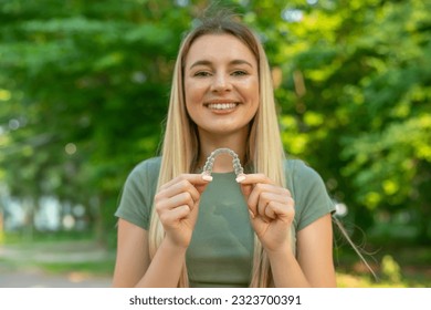 Women hand hold inivisalign braces, transparent aligner, invisible retainer or orthodontic silicone trainer with blur mile in background. A way to have a beautiful smile. - Powered by Shutterstock