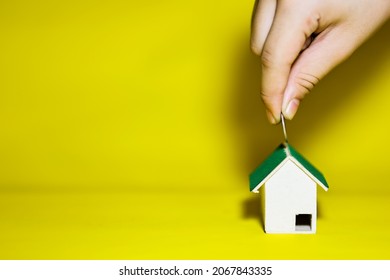 Women Hand Holding Coin Over House Model. Real Estate Or Property Investment Growing Business. Home Mortage Loan Rate.