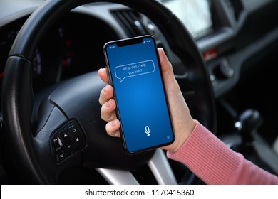 women hand holding phone with app personal assistant on screen in the car