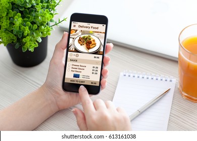 Women Hand Holding Phone With App Delivery Food On Screen Above Desk 