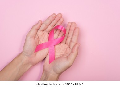 women hand holding pink ribbon breast cancer on pink background. with copy space - Shutterstock ID 1011718741