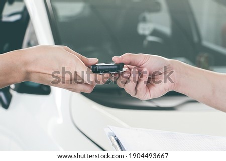 Women hand and Men hand giving modern key of car with car background. transportations concept. Sell or buy new car concept. Maintenance concept.