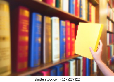 Women Hand Pulling Yellow Book From Wood Bookshelves In Public Philosophy Library. Colorful Books, Textbook, Literatur On Bookshelf.