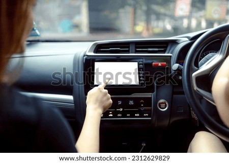 Women hand touching a multimedia system with an isolated screen in car. Hand push button in modern car with copy space on monitor screen