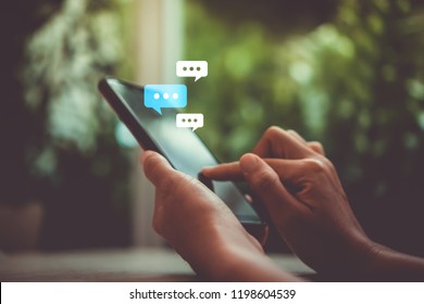 Women hand using smartphone typing, chatting conversation working home in chat box icons pop up. Social media maketing technology concept.Vintage soft color tone background.