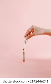 Women Hands Hold  Lipstick For Make Up Isolated On Pink Background With Copy Space.