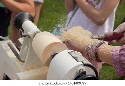 Women Hands Holding A Chisel Near The Lathe, A Woman Working On A Small Wooden Lathe, A Craftsman Cuts A Piece Of Wood With A Hand Lathe