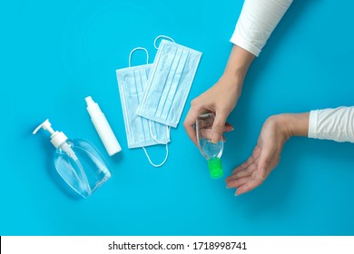 Women hands holding hand sanitizer with alcohol spray and surgical mask on blue background - Powered by Shutterstock