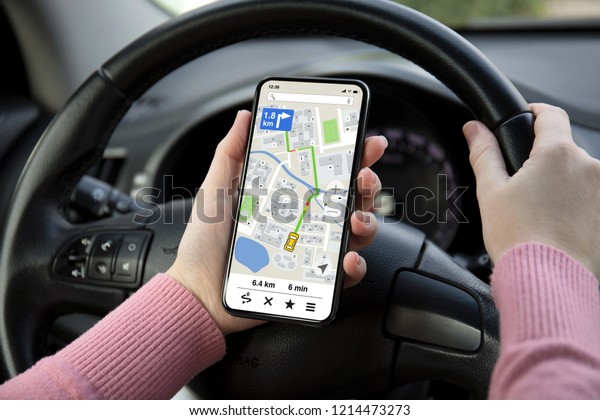 women hands holding phone with app navigation map on\
screen in the car