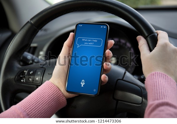 women hands holding phone with app personal assistant\
on screen in the car