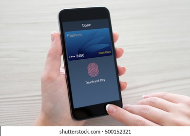 Women hands holding phone with debit card on the screen over table