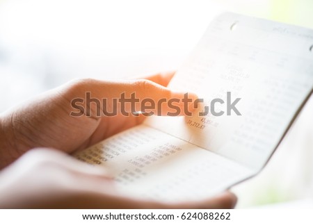 Women hands holding saving account passbook, book bank  laptop background