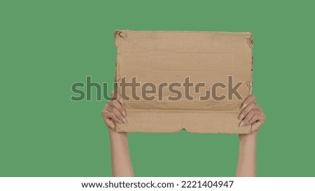 Women hands raising blank poster from a cardboard box. Blank space for your slogan, logo or advertisement. Banner design concept. Cardboard sign for requirements, promotion, advertising.