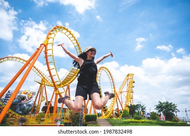a women has fun happy joy day at amusement park in summer sunny day, roller coaster, jumping girl, vacation leisure holiday, activities concept. asian women, nice clear blue sky. enjoy moment