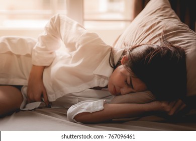 Women Have Abdominal Pain Because Of Menstruation. She Was Lying In Bed And Holding Her Stomach. Her Expression Shows The Pain.