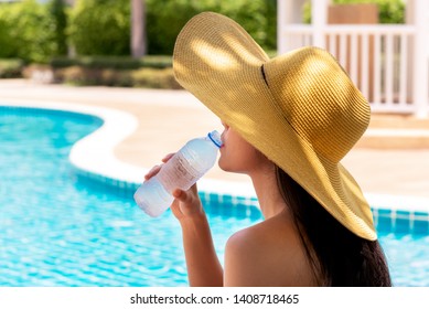 Women have long hair, wearing a big hat Drinking cold water from plastic bottles Near the pool, to summer concept. - Powered by Shutterstock