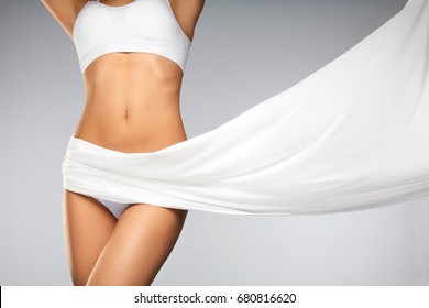 Women Health. Beautiful Healthy Woman With Fit Slim Body, Silky Smooth Soft Skin In White Bikini Underwear. Closeup Of Textile Flying On Perfect Female Body Shape. Body Care Concept. High Resolution