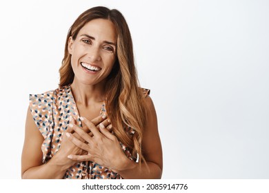 Women Health And Beauty. Happy Middle Aged 40s Woman In Dress, Smiling And Looking Pleased, Holding Hands On Chest With Thankful Face Expression, White Background