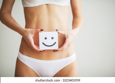 Women Health. Closeup Of Healthy Female With Beautiful Fit Slim Body In White Panties Holding White Card With Happy Smiley Face In Hands. Stomach Health And Good Digestion Concepts. High Resolution - Shutterstock ID 1023401959